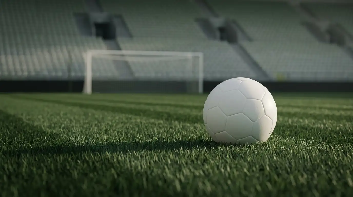 Ballon de football posé sur la pelouse d'un stade vide après un match, filet de but en arrière-plan